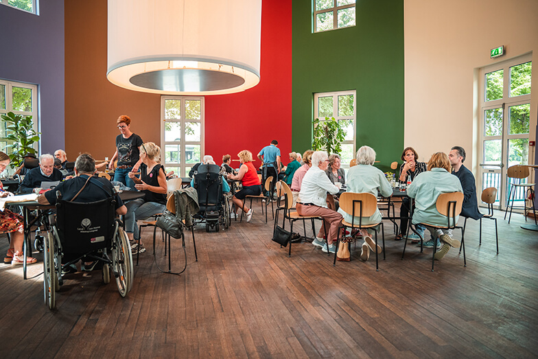 Een groep ouderen zit in een museumrestaurant.