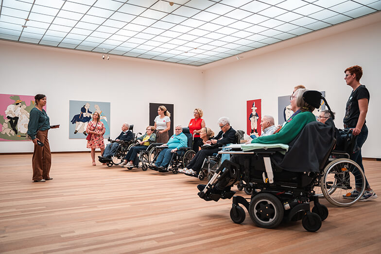 Een groep ouderen met rolstoel en begeleiders kijken naar kunstwerken in het Bonnefanten.