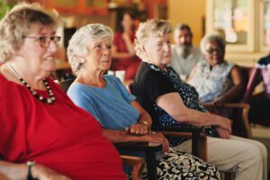 Een groep ouderen kijkt met een glimlach naar de museumdocent